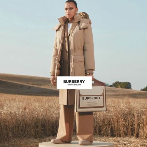 Burberry Kollektion – Model in Burberry-Jacke mit Tasche auf Podest vor Weizenfeld, eleganter Lifestyle bei Closory