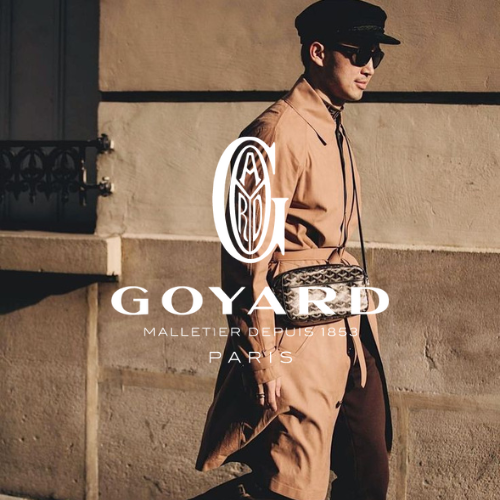 Goyard Kollektion – Model vor grau-beiger Wand in braunem Trenchcoat mit Mütze und Goyard Tasche, eleganter Lifestyle bei Closory