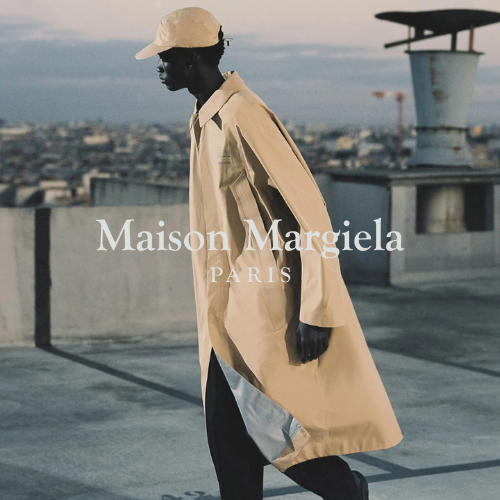 Maison Margiela Kollektion – Model in beigem Mantel steht auf Dach im Wind, avantgardistischer Lifestyle bei Closory