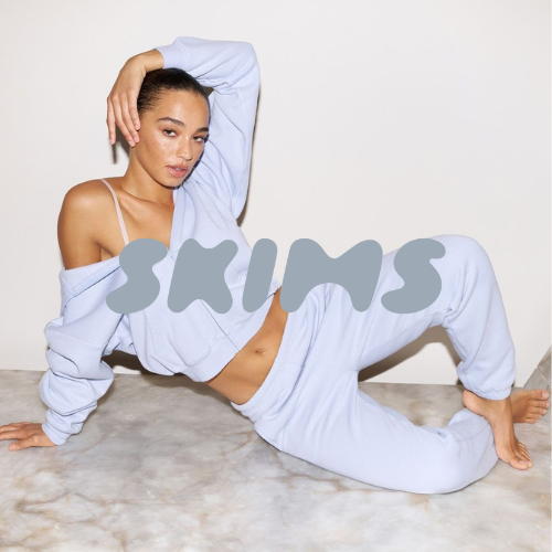 Skims Kollektion – Model in Nachtmode liegt posend auf grauem Boden, moderner Lifestyle bei Closory