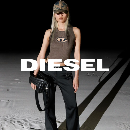 Diesel Kollektion – Frau auf Sand stehend vor dunklem Hintergrund in Top, Jeans und Tasche von Diesel, lässiger Lifestyle bei Closory