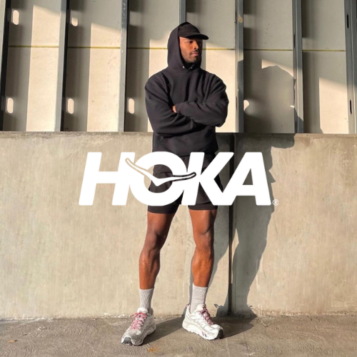 Hoka Kollektion – sportlicher Mann in Hoodie und Shorts in Hoka Schuhen vor Gebäude, aktiver Lifestyle bei Closory