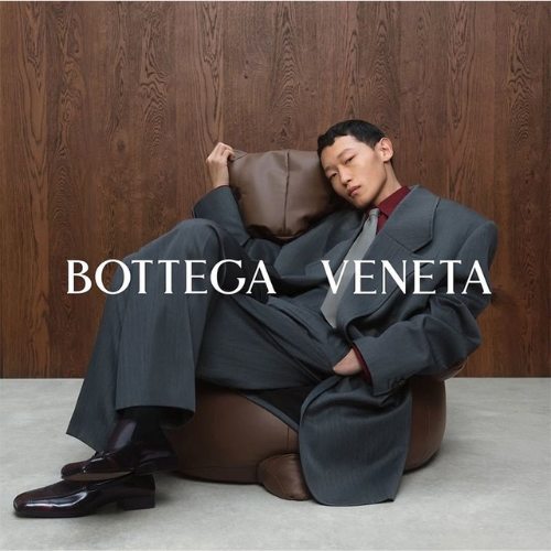 Bottega Veneta Kollektion – Model in grauem Anzug auf braunem Ledersitzsack, eleganter Lifestyle bei Closory