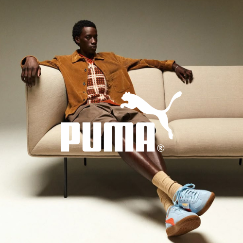 Puma Kollektion – Mann mit Sneakers liegt auf einer Couch in einem leeren Raum, sportlicher Lifestyle bei Closory
